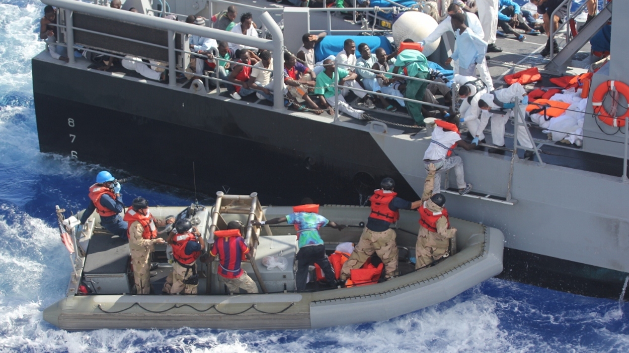 Distressed persons are transferred to a Maltese patrol vessel.