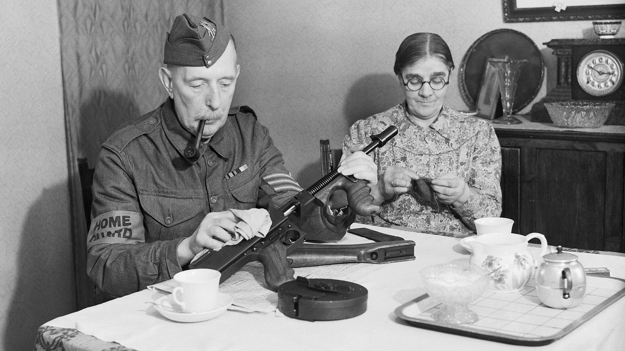 1920px-A_veteran_sergeant_in_the_Dorking_Home_Guard_cleans_his_Tommy_gun_at_the_dining_room_table,_before_going_on_parade,_1_December_1940._H5850