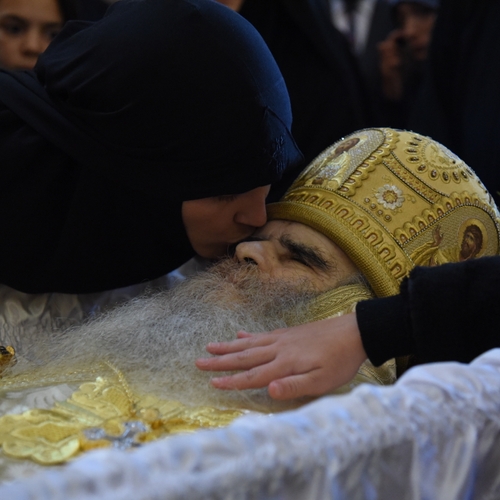 Rouwende gelovigen kussen het lijk van aan corona overleden bisschop